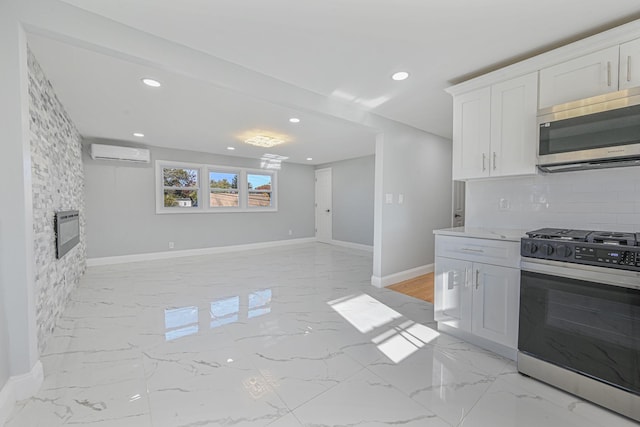 kitchen with a stone fireplace, range with gas cooktop, a wall mounted AC, white cabinets, and backsplash