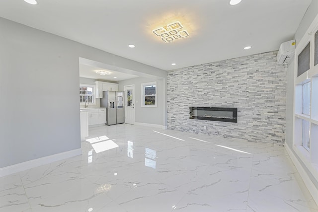 unfurnished living room with an AC wall unit, a large fireplace, and sink