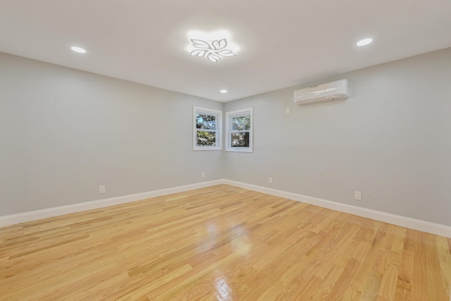 spare room with light hardwood / wood-style flooring and an AC wall unit