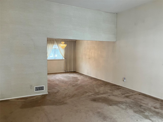 carpeted spare room featuring an inviting chandelier