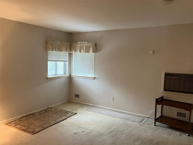 empty room with a wall mounted air conditioner and light colored carpet