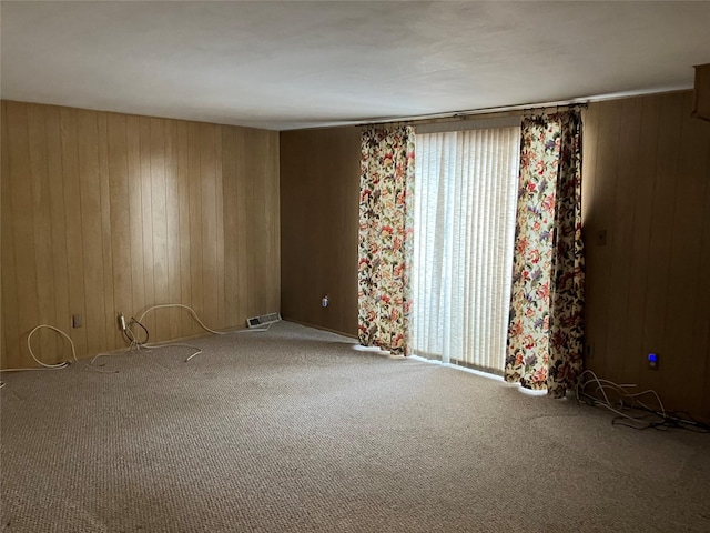 unfurnished room featuring carpet and wood walls