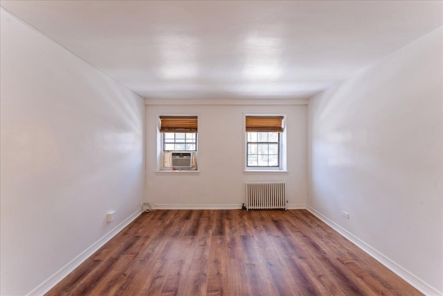 spare room with cooling unit, dark wood-type flooring, and radiator heating unit