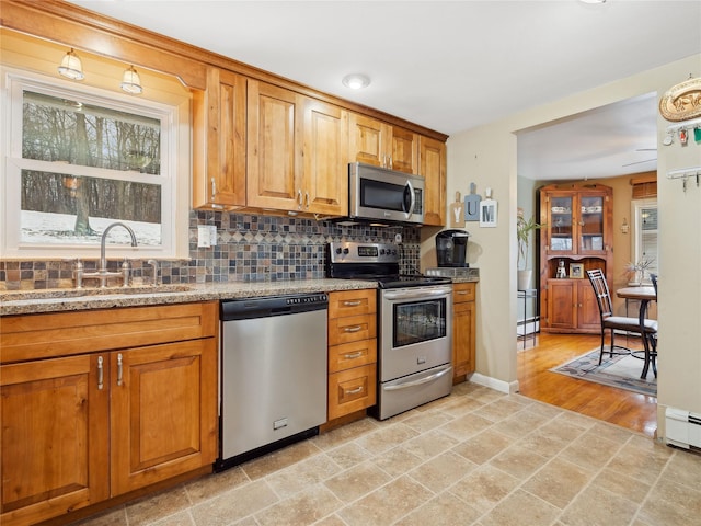 kitchen featuring sink, decorative backsplash, stainless steel appliances, and light stone countertops