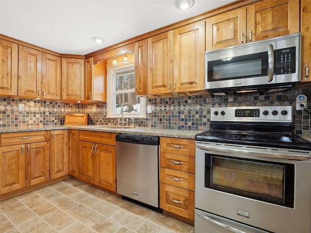 kitchen featuring appliances with stainless steel finishes, light stone countertops, sink, and backsplash