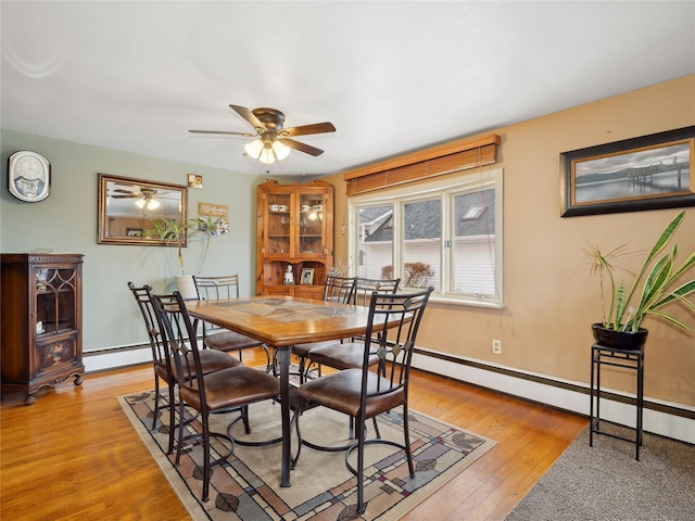 dining area with ceiling fan, a baseboard radiator, and light hardwood / wood-style floors