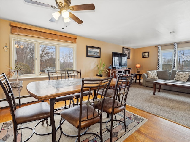 dining space featuring a baseboard heating unit, ceiling fan, and light hardwood / wood-style flooring