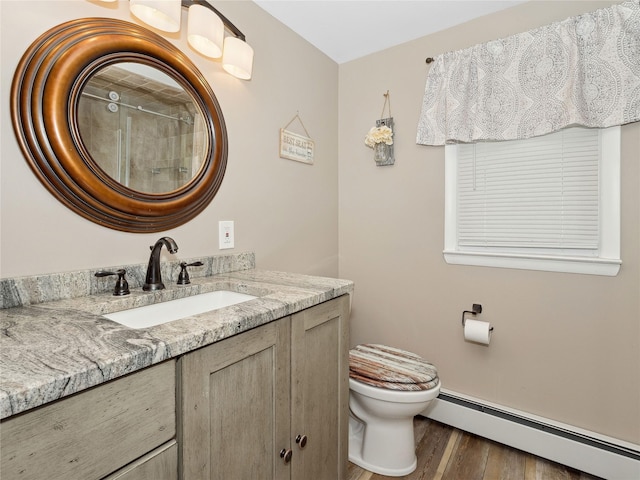 bathroom featuring vanity, hardwood / wood-style flooring, toilet, and baseboard heating