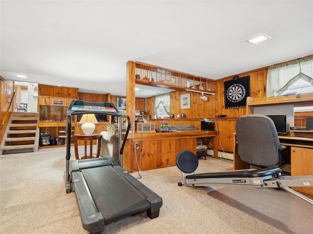 exercise area featuring wooden walls, light colored carpet, baseboard heating, and a workshop area