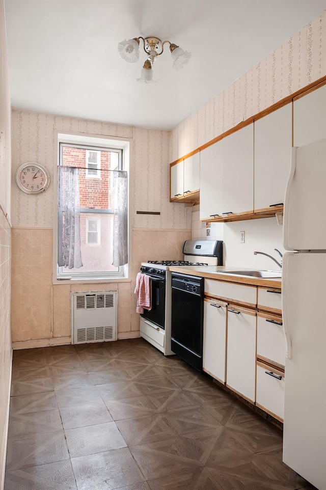 kitchen with white cabinetry, radiator heating unit, sink, and white fridge