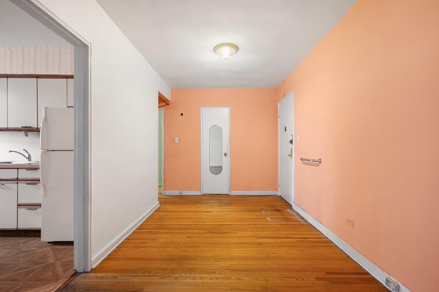 corridor featuring sink and light hardwood / wood-style flooring