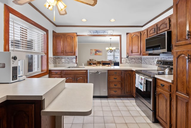 kitchen featuring decorative light fixtures, sink, backsplash, ornamental molding, and stainless steel appliances