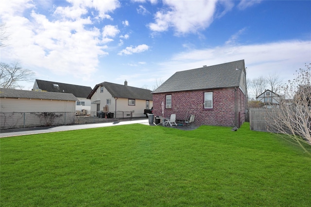 back of house with brick siding, a patio area, fence, and a yard