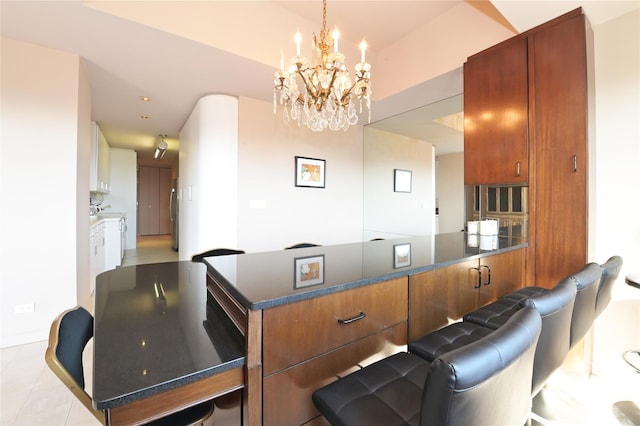 interior space featuring brown cabinets, dark stone counters, a chandelier, and a peninsula