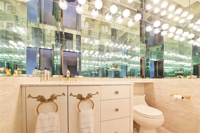 bathroom with visible vents, tile walls, a sink, and toilet