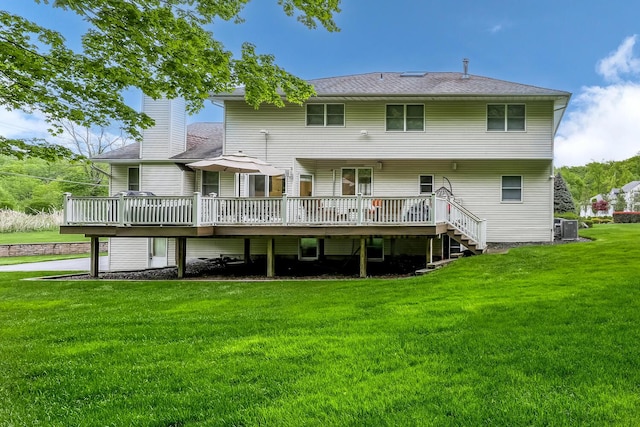 rear view of property with cooling unit, a chimney, a yard, and a deck