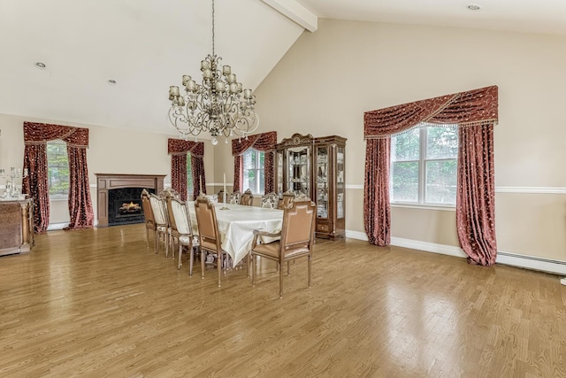 dining room featuring beamed ceiling, baseboard heating, light wood-style flooring, and a healthy amount of sunlight