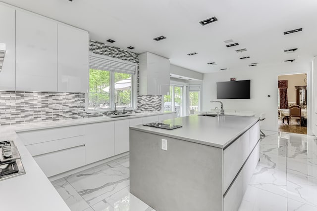 kitchen featuring marble finish floor, light countertops, a kitchen island, and white cabinetry