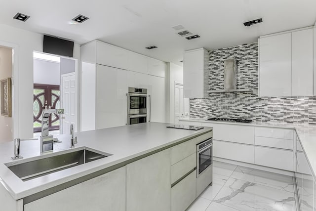 kitchen with appliances with stainless steel finishes, light countertops, a sink, and wall chimney exhaust hood