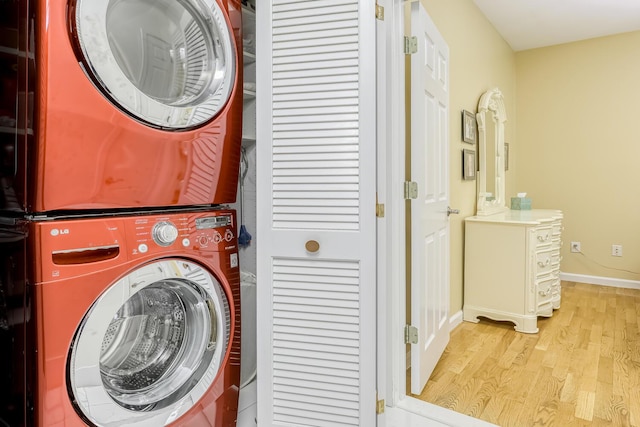 washroom featuring light wood-style floors, stacked washer and clothes dryer, baseboards, and laundry area