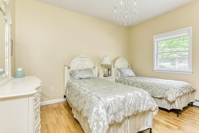 bedroom with a notable chandelier, light wood-style flooring, and baseboards