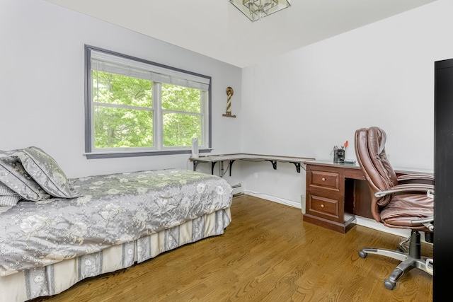 bedroom with baseboards, baseboard heating, and wood finished floors