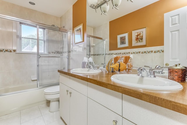 bathroom featuring combined bath / shower with glass door, tile patterned flooring, a sink, and tile walls