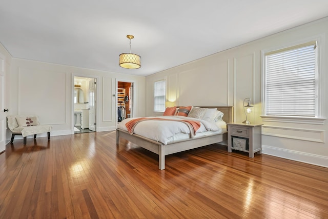 bedroom with a walk in closet and wood-type flooring