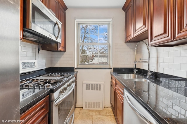 kitchen with appliances with stainless steel finishes, sink, dark stone countertops, and decorative backsplash