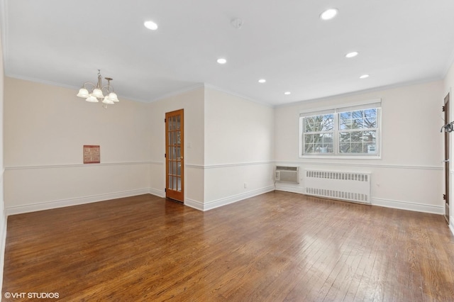 unfurnished room with dark hardwood / wood-style flooring, a notable chandelier, crown molding, and radiator heating unit