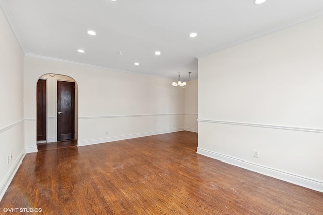 spare room featuring crown molding, an inviting chandelier, and dark hardwood / wood-style flooring