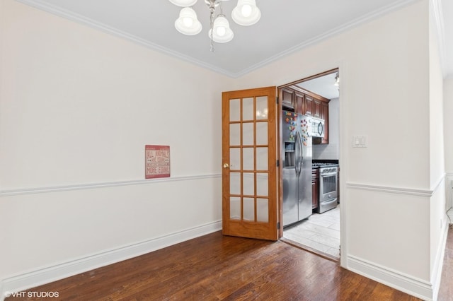 unfurnished dining area featuring wood-type flooring, ornamental molding, and a chandelier