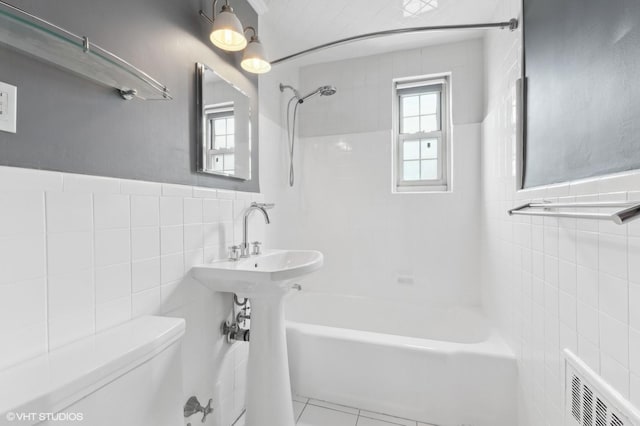 bathroom featuring tiled shower / bath, tile patterned floors, toilet, and tile walls