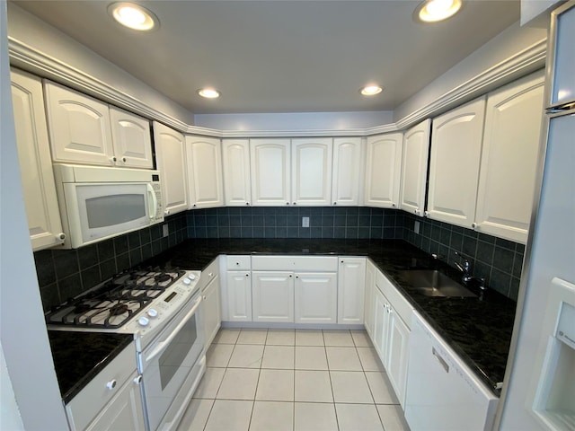 kitchen with sink, white appliances, white cabinets, decorative backsplash, and dark stone counters
