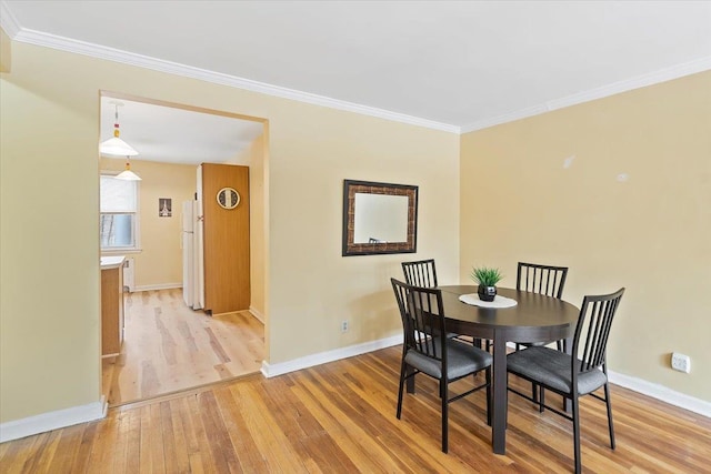 dining space featuring crown molding and light hardwood / wood-style flooring