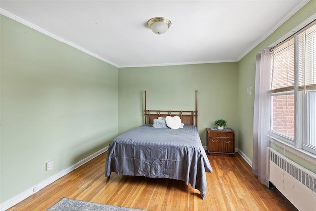 bedroom with ornamental molding, radiator, and light hardwood / wood-style floors