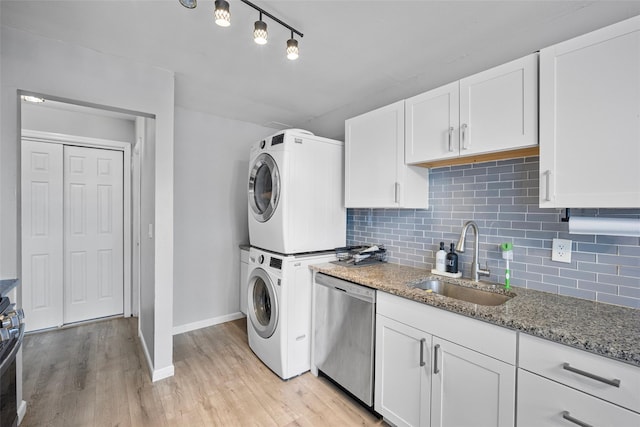 kitchen with decorative backsplash, dishwasher, stacked washing maching and dryer, white cabinetry, and a sink