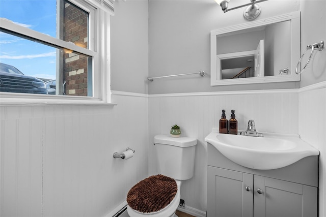 half bath featuring a wainscoted wall, vanity, and toilet