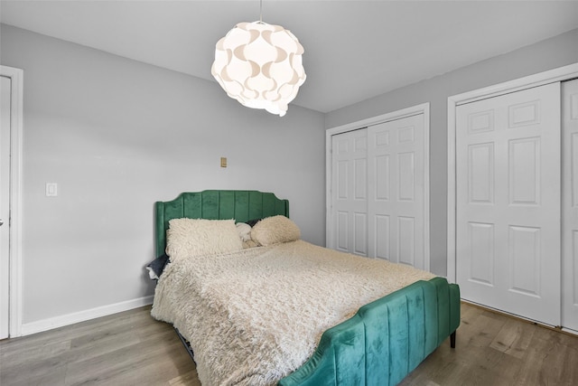 bedroom featuring a notable chandelier, a closet, baseboards, and wood finished floors