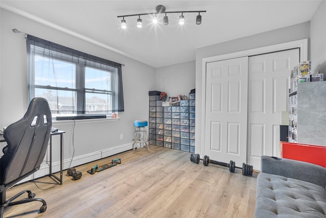 office space featuring a baseboard radiator, baseboards, and wood finished floors