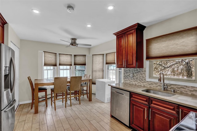 kitchen with stainless steel appliances, sink, backsplash, and light wood-type flooring