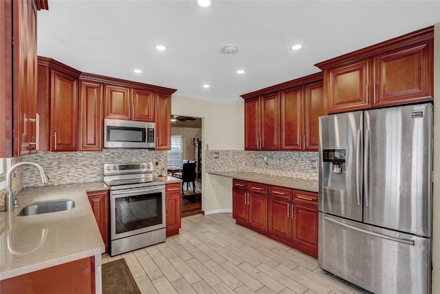 kitchen with decorative backsplash, appliances with stainless steel finishes, sink, and light hardwood / wood-style flooring