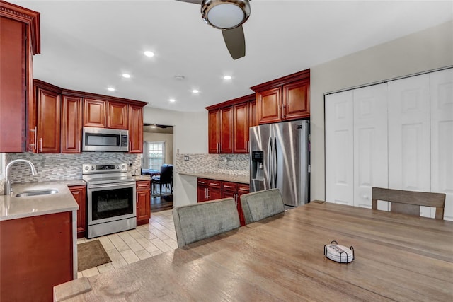 kitchen with appliances with stainless steel finishes, light hardwood / wood-style floors, sink, and decorative backsplash