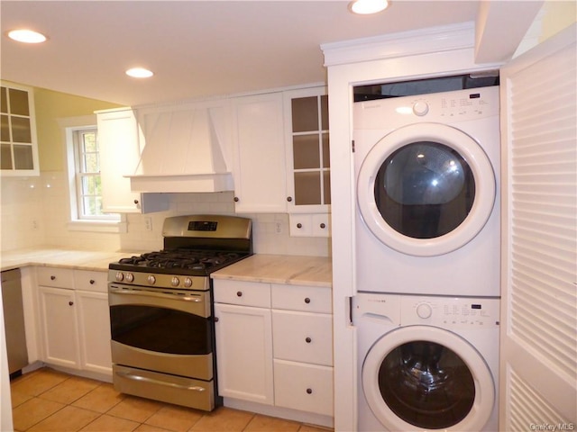 clothes washing area featuring stacked washing maching and dryer and light tile patterned floors