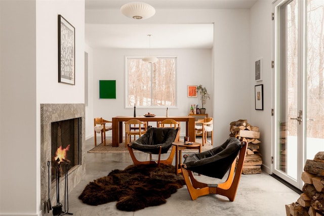 sitting room featuring concrete flooring and a lit fireplace