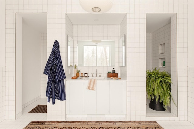 bathroom featuring tile patterned flooring, a sink, and tile walls