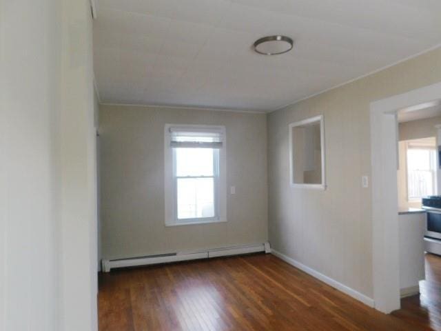 unfurnished room featuring dark hardwood / wood-style flooring and baseboard heating