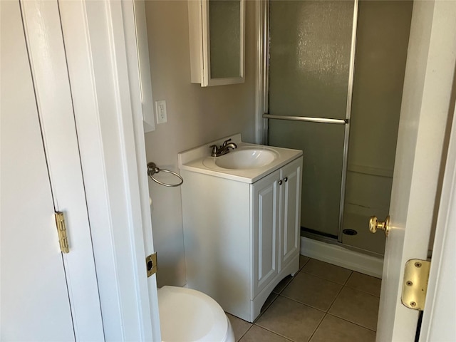 bathroom with tile patterned flooring, an enclosed shower, vanity, and toilet