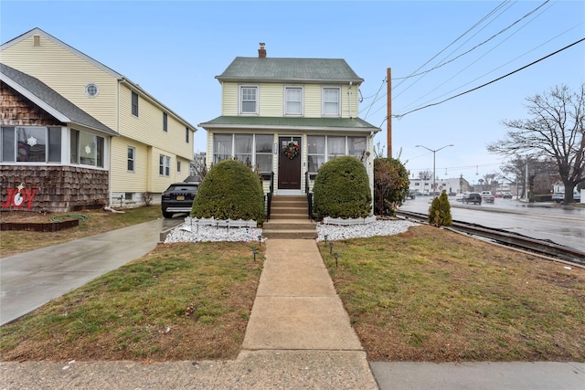 view of front of property featuring a sunroom and a front lawn