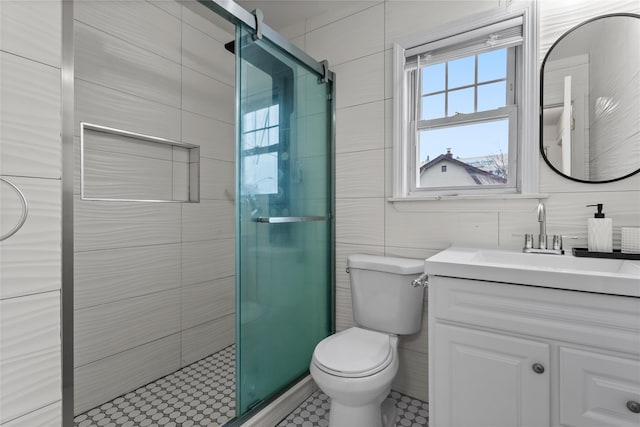 bathroom with walk in shower, vanity, toilet, and tile walls